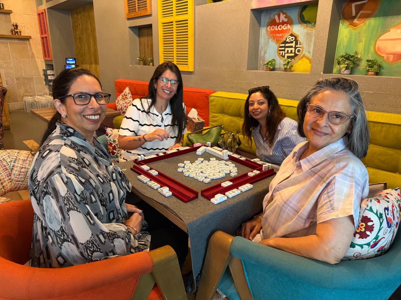 Women playing Mahjong together at a warm Dubai lounge table