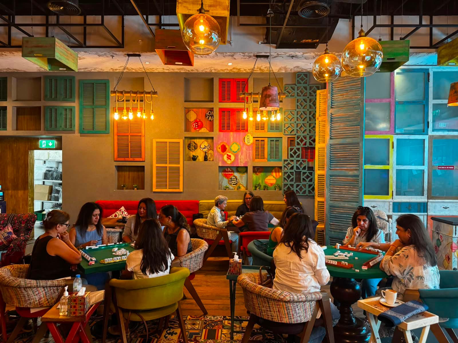 Multiple Mahjong tables active in a vibrant, beautifully decorated Dubai cafe venue